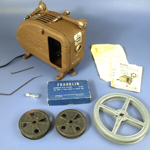 Proiettore cinematografico vintage Excel modello P46 da 16 mm con taglia-pellicola Franklin, bobine e manuale - Funzionante ma necessita di nuove cinghie di trasmissione a molla - Epoca Art Déco