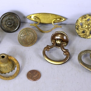 以下が含まれることがあります： アンティークブラスのキャビネットノブとプル8個の詰め合わせ。正方形のノブには花柄、丸いノブには花柄、渦巻き柄、盛り上がったデザイン、曲線的なハンドル、ストレートハンドル、ループハンドル、D字型のハンドルがあります。