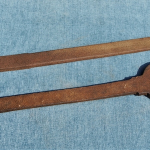 Peut inclure: Deux clés à molette rouillées avec de longues poignées. Les clés sont en métal et ont une ouverture arrondie à l'extrémité de la poignée.