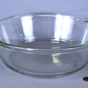 Op de afbeelding: Een glazen ovenschaal met twee handvatten. De schaal is rond en heeft een glad, glanzend oppervlak.