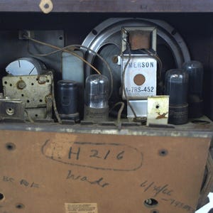 Puede incluir: Vista interior de una radio Emerson vintage con un altavoz, varios tubos de vac&iacute;o y una etiqueta que dice "Emerson A-7RS-452". La radio tiene un gabinete de madera y una etiqueta manuscrita en la parte posterior que dice "(L)H 216 brade 4/reflect - 11588".