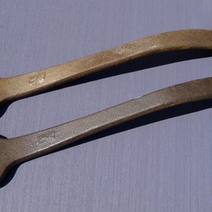 May include: Two rusty wrenches with different sized openings. The wrench on top has a hexagonal head and the wrench on the bottom has a rounded head.