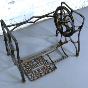 May include: Black cast iron sewing machine base with a large wheel and a foot pedal. The base is marked "White Sewing Machine Co."