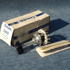 May include: A vintage Centralab rotary switch with a black handle, a cream-coloured ceramic body, and multiple terminals. The switch is accompanied by its original cardboard box and a small instruction booklet. The box is labelled "Centralab" and "2503".