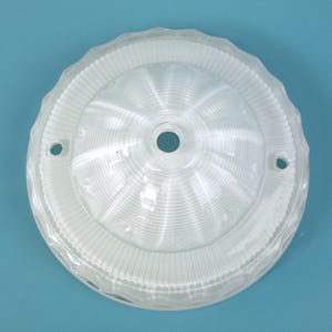 May include: A round, clear glass light fixture shade featuring a central dome with horizontal ribbed detailing. The outer edge has a scalloped, wavy rim. Two small circular mounting holes are positioned on opposite sides of the flat border.