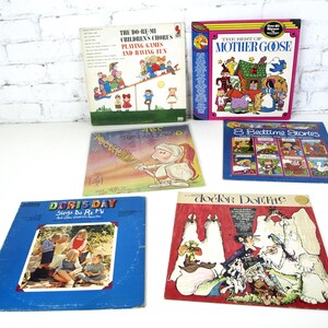 Może przedstawiać: Kolekcja starych płyt dla dzieci z kolorowymi ilustracjami i tytułami takimi jak "The Do-Re-Mi Children's Chorus", "The Best of Mother Goose" i "Doris Day Sings Do Re Mi". Płyty są ułożone na białej powierzchni.