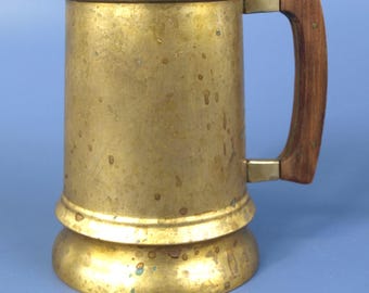 Jarra de cerveza antigua de latón macizo con asa de madera, de mediados del siglo XX.
