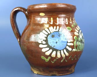 Jarra de leche antigua de cerámica roja pintada a mano, arte popular de principios del siglo XX.