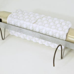 May include: A white milk glass lamp with a textured surface and a beige ceramic base. The lamp is mounted on a metal bracket with two hooks.