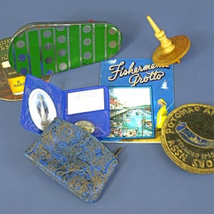 May include: A collection of vintage items including a green and silver striped tin, a wooden spinning top, a Guinness coaster, a blue wallet with a religious icon, a Fishermen's Grotto postcard, and a round Potomac Arms Collectors Assn patch.