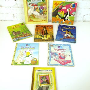 May include: A collection of vintage children's books, including titles like "Cabbage Patch Kids," "Aladdin," and "Tom & Jerry." The books feature colorful illustrations and text, with titles and characters prominently displayed on the covers.