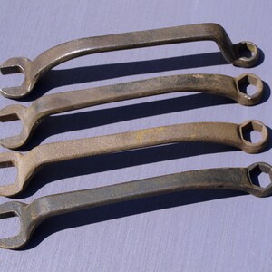 Può includere: Quattro chiavi inglesi arrugginite con teste esagonali e manici curvi. Le chiavi sono disposte in fila, con la chiave più grande in alto e la chiave più piccola in basso.