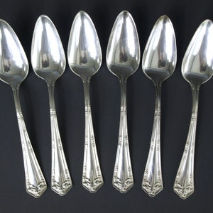 Puede incluir: Seis cucharaditas de plata con mangos adornados. Las cucharas tienen un cuenco redondeado de forma ovalada y un mango largo y delgado.