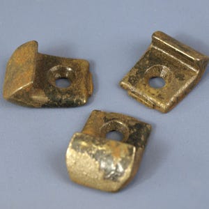 May include: Three rusty metal hooks with a rounded edge and a hole in the center. The hooks are a dark brown color with black and silver accents.