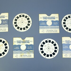 May include: A collection of vintage View-Master reels and their packaging. The reels are circular with small rectangular viewing windows. The packaging is rectangular with a circular cutout and text that reads "View-Master Reel".