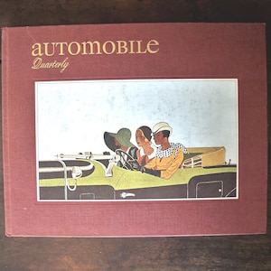 以下が含まれることがあります： 金色の文字で「automobile Quarterly」と書かれたヴィンテージ本の表紙。表紙には、緑と黒のコンバーチブルカーに乗った3人のイラストが描かれています。本は赤茶色の表紙です。