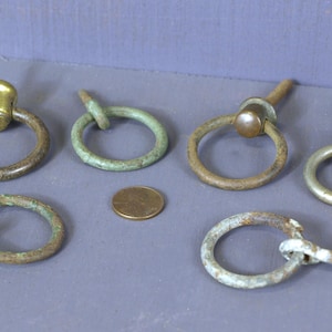 May include: Five antique brass and iron ring pulls with a screw back. The ring pulls are in various sizes and styles.