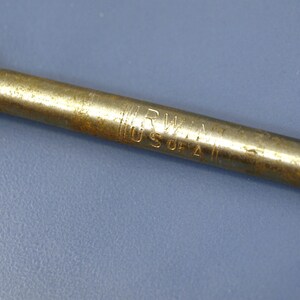 May include: Close-up of a vintage metal tool with a brass finish. The tool has the inscription "IRWIN USA 2" etched into the metal. The tool is set against a blue background.