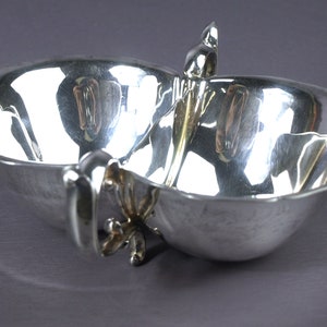 May include: A silver double-handled serving dish with a scalloped edge and a decorative handle.