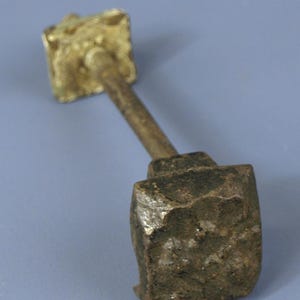 May include: A vintage metal door handle with a square top and a square bottom. The top is made of brass and the bottom is made of iron.