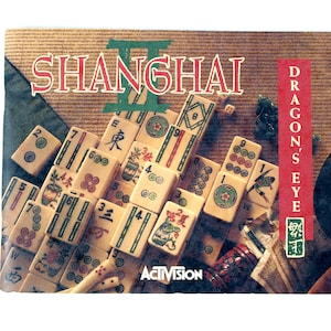 May include: The box cover for the board game Shanghai II: Dragon's Eye features a stack of ivory-colored mahjong tiles. The game title is in red and green, with the Activision logo at the bottom. The game's theme is visible in the image.