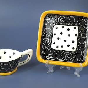 Taza y plato de cerámica "Lunas y estrellas" de Robin Spear Pottery en negro, blanco y naranja