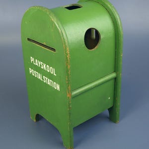 May include: A vintage green wooden Playskool Postal Station toy mailbox. The mailbox has a slot for mail, a round opening, and the words "Playskool Postal Station" in white lettering. The toy is painted green with some visible wear and tear.