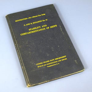 Puede incluir: Un libro negro antiguo con letras doradas. El título es "STABILITY AND COMPARTMENTATION OF SHIPS". La portada dice "RESTRICTED - For Official Use Only" y "C. AND R. BULLETIN No. 14". Es del Departamento de la Marina de los Estados Unidos.