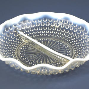 Puede incluir: Un plato de servir dividido en dos partes, hecho de vidrio transparente con un borde blanco. El plato tiene un borde festoneado y una superficie texturizada, con burbujas.