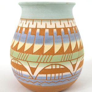 Könnte beinhalten: Eine handbemalte Keramikvase mit einem südwestlichen Design. Die Vase ist mit geometrischen Mustern in Braun-, Blau-, Grün- und Weißtönen verziert.