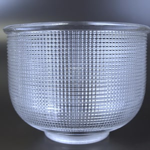 May include: A clear glass bowl featuring a textured grid pattern across its exterior surface. The design consists of intersecting horizontal and vertical lines that create a repeating square motif, with a smooth rim and a circular base.