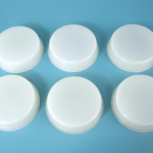 May include: A set of six circular, translucent white silicone molds arranged in two rows of three. Each mold features a flat top surface with a slightly raised rim and a smooth, rounded edge, designed for casting or crafting purposes.