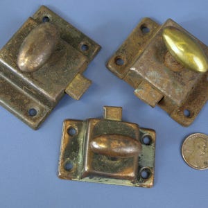 May include: Three antique brass door latches with different styles of handles. The latches are all in various shades of brass and have a worn, aged look.
