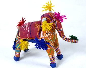 May include: A colorful handmade stuffed elephant toy with embroidered details and pom-poms. The elephant is made of fabric in shades of pink, orange, blue, green, and yellow.