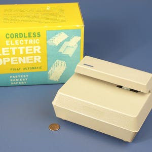 May include: A beige cordless electric letter opener with the words "Cordless Electric Letter Opener" and "Fully Automatic" on the box. The box also says "Fastest Easiest Safest".