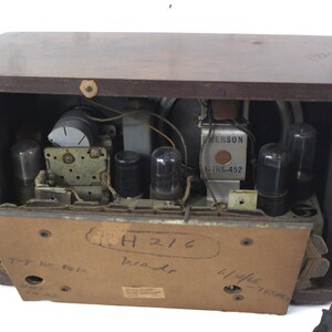 Puede incluir: Una radio Emerson vintage con un gabinete de madera. La parte posterior de la radio est&aacute; abierta, revelando los componentes internos, incluidos varios tubos de vac&iacute;o y un altavoz. La radio tiene una etiqueta que dice "Emerson 47RS-452" y "H216" escrito en la parte posterior.