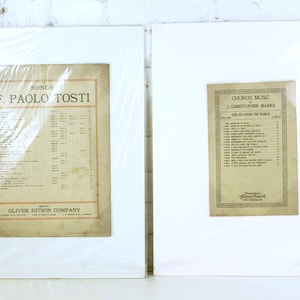 Puede incluir: Dos impresiones enmarcadas de partituras antiguas. La impresión de la izquierda presenta "Songs" de F. Paolo Tosti, publicada por Oliver Ditson Company. La impresión de la derecha es "Church Music" de J. Christopher Marks, titulada "God So Loved the World".