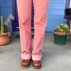 K&ouml;nnte beinhalten: Hellrosa Cordhose mit umgeschlagenem Saum, kombiniert mit braunen Clogs. Die Clogs haben Holzsohlen. Das Outfit ist l&auml;ssig und bequem. Die Hose ist einfarbig.