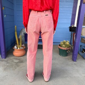 K&ouml;nnte beinhalten: Hellrosa Cordhose mit hohem Bund und geradem Bein. Die Person tr&auml;gt ein rotes Langarmhemd. Die Hose ist einfarbig und hat Taschen auf der Vorder- und R&uuml;ckseite. Der Markenname ist sichtbar.