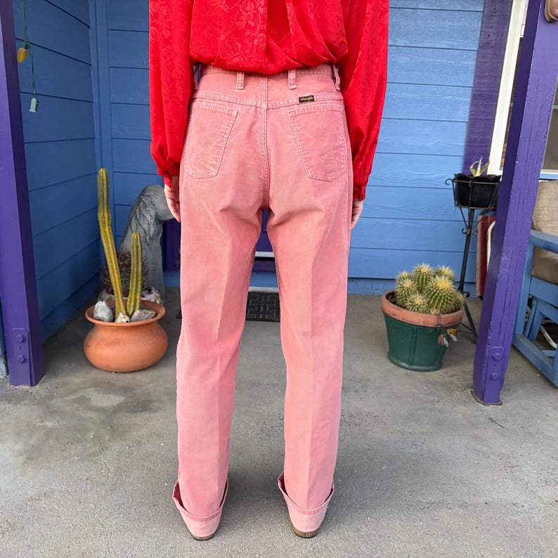 K&ouml;nnte beinhalten: Hellrosa Cordhose mit hohem Bund und geradem Bein. Die Person tr&auml;gt ein rotes Langarmhemd. Die Hose ist einfarbig und hat Taschen auf der Vorder- und R&uuml;ckseite. Der Markenname ist sichtbar.