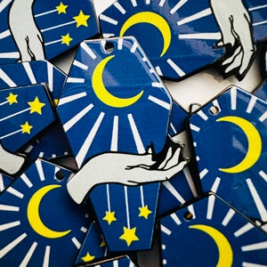 May include: A collection of blue and white hexagonal shaped ornaments with a crescent moon and stars design. The ornaments have a white hand reaching up towards the moon.