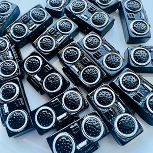 May include: A collection of black and silver miniature boombox charms. The charms are made of resin and have a detailed design.