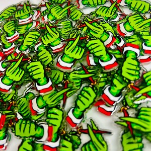 May include: A collection of green hand-shaped pins, each holding a red object. The hands have white cuffs with red trim. The pins are scattered across a white surface, creating a playful and festive design.