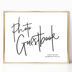 May include: A gold-framed sign with black text that reads "Photo Guestbook" and "Thank you for celebrating with us!"