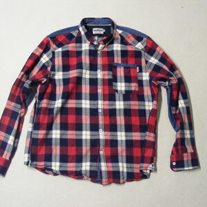 May include: A long-sleeved plaid shirt in red, navy, white, and gray. The shirt features a button-down front, a chest pocket, and a contrasting blue fabric on the shoulders and cuffs. The shirt has a classic, casual style.