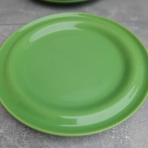 May include: A stack of bright green ceramic plates. The plates have a smooth, glossy finish and a simple, modern design. The plates are a vibrant shade of green, perfect for adding a pop of color to any table setting.