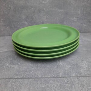 May include: A stack of four oval-shaped, light green plates. The plates are stacked neatly on top of each other, with a slight lip around the edge. The plates are a solid, bright green color.