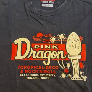 May include: Black t-shirt with a red and yellow graphic of a pink dragon with the text "Pink Dragon", "Toropical-Deco & Rock'n'Roll", "23-23-1 South Cat Street. Harajuku, Tokyo".