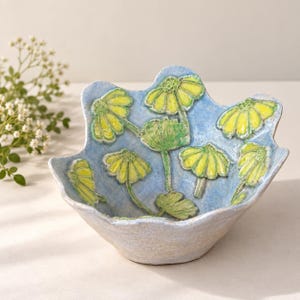 Handmade stoneware bowl with raised daisies, wavy rim, blue floral pottery