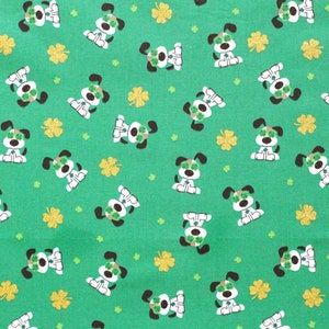 May include: Green fabric with a repeating pattern of white dogs wearing shamrock eye patches. The dogs are sitting with their paws crossed and have black noses and eyes. The background is a solid green with gold glitter shamrocks scattered throughout.